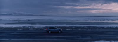 a car driving down a road next to a large body of water