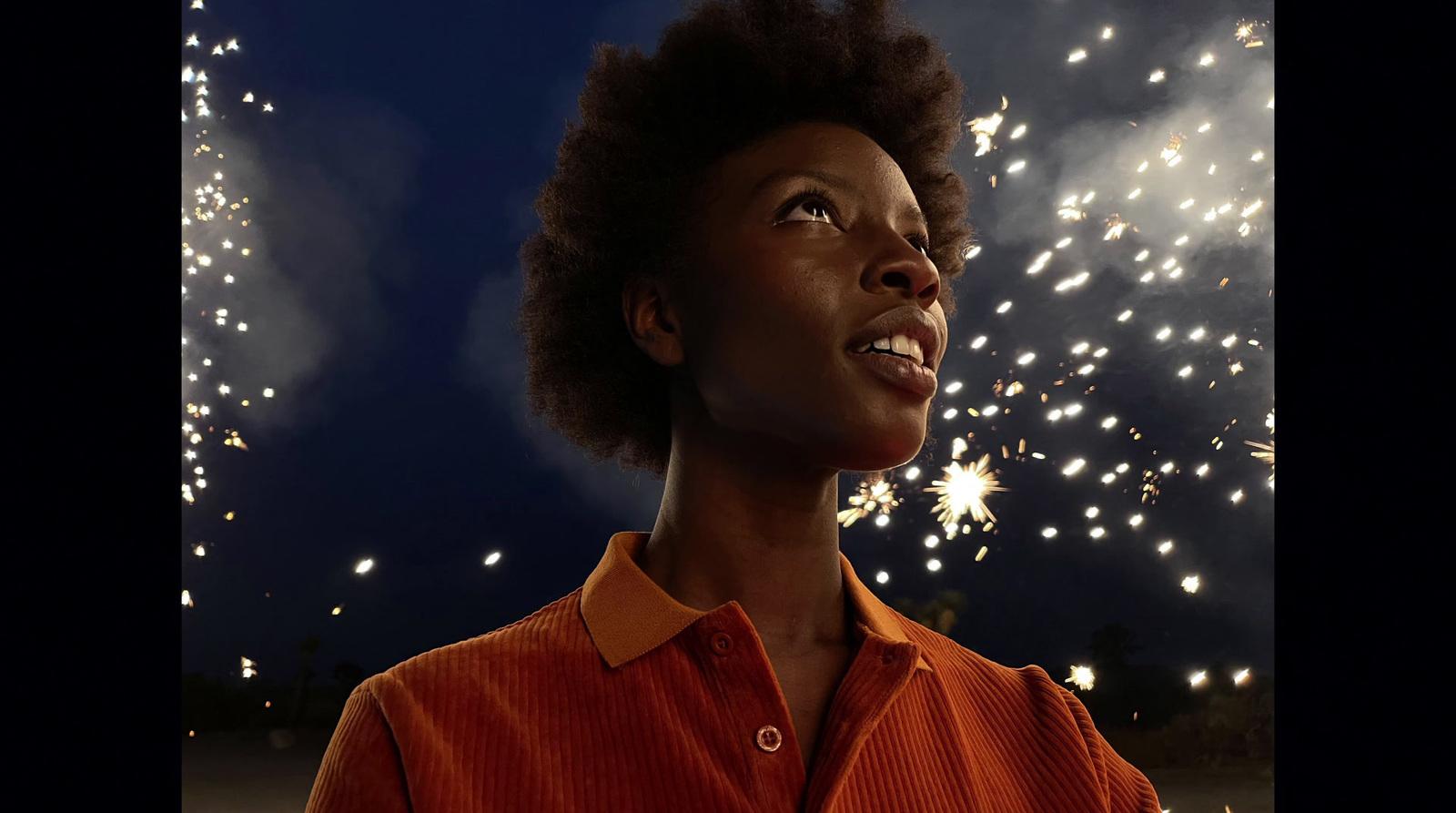 a woman looking up at fireworks in the sky