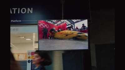 a woman is walking past a television screen