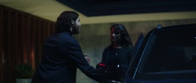 a man and a woman shaking hands in front of a car