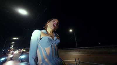 a woman standing in the middle of a street at night