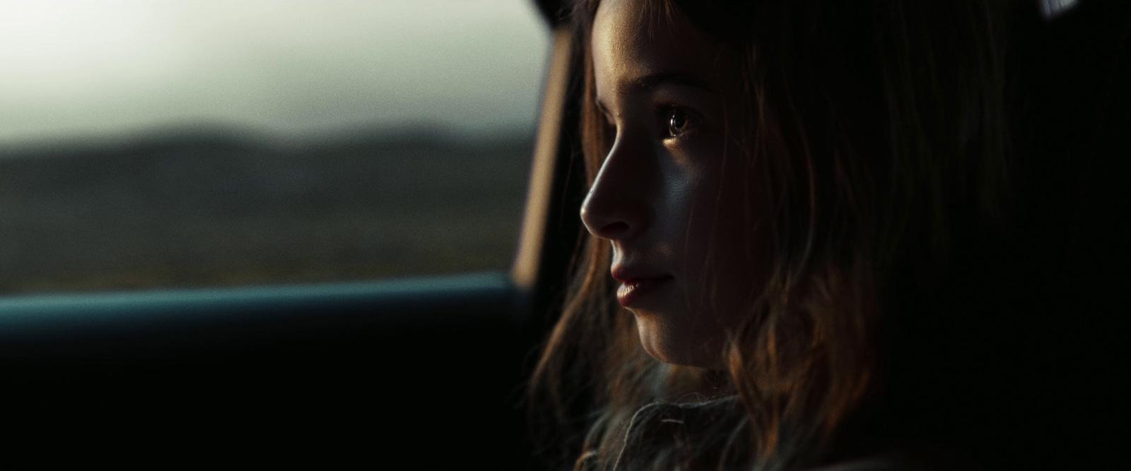 a young girl sitting in the passenger seat of a car