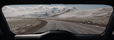 a view of a snowy mountain range from inside a vehicle