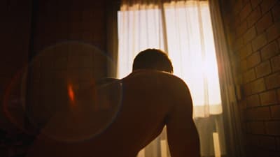 a shirtless man standing in front of a window