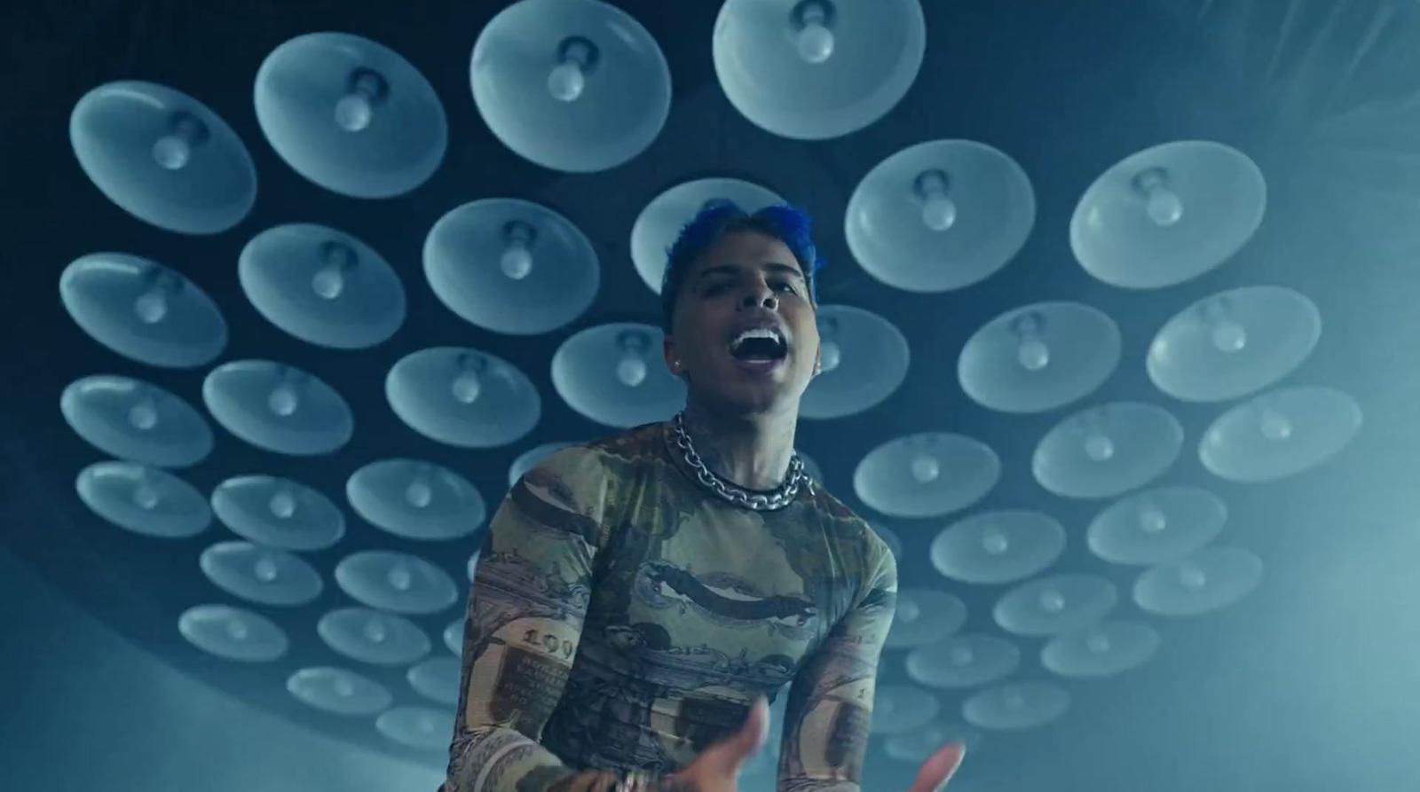 a man with blue hair singing into a microphone