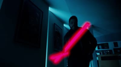 a man holding a red light saber in a dark room