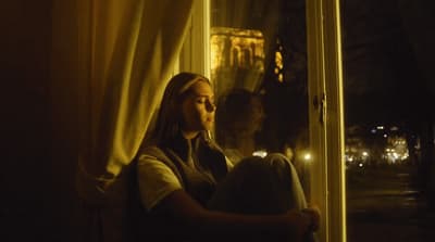 a woman sitting on a window sill looking out the window