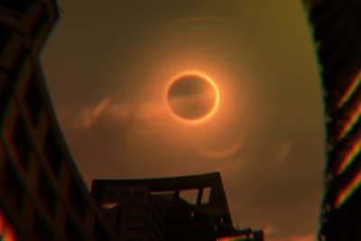a solar eclipse seen through a pair of buildings