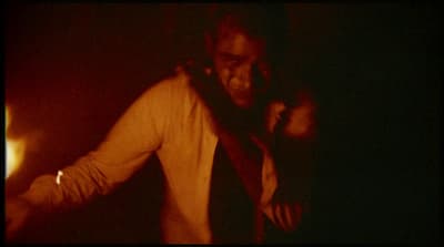 a man standing in a dark room with his hands on his hips