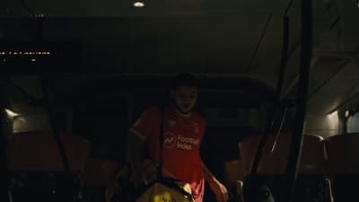 a man in a red shirt standing next to a bus