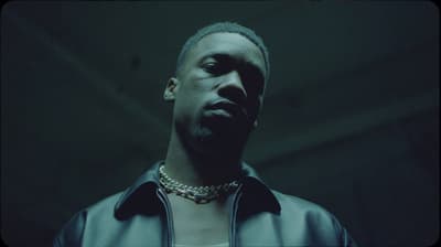 a man in a leather jacket with a chain around his neck