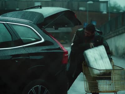 a man pushing a shopping cart with a mattress in it