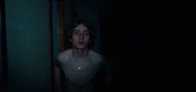 a shirtless man standing in a dark room