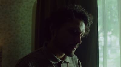 a man standing in front of a window looking at his cell phone