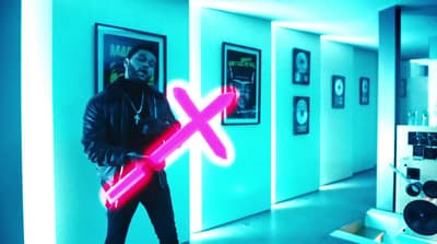 a man standing in a room holding a neon pink light saber