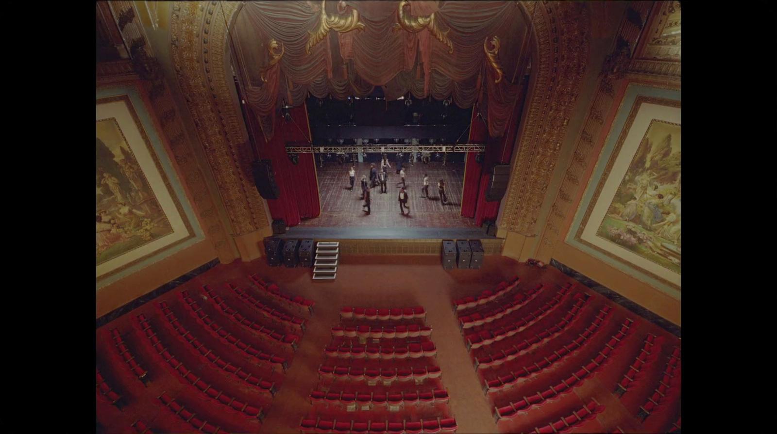 an empty theater with red seats and a ladder