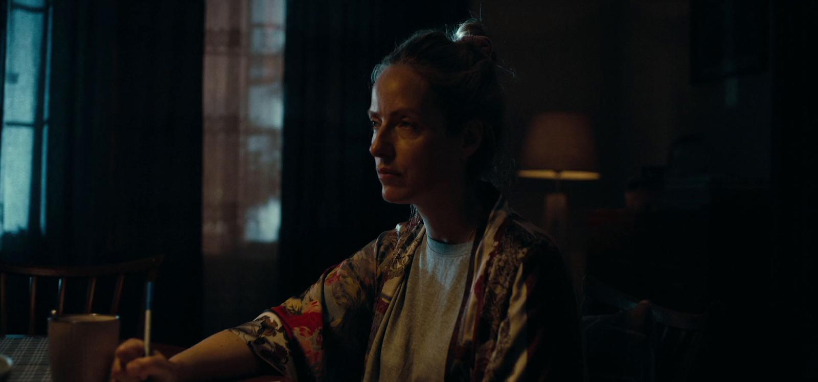 a woman sitting at a table in a dark room