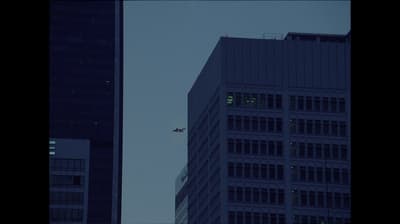 a plane flying in the sky over a tall building