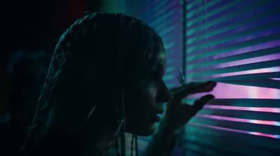 a woman standing in front of a window covered in blinds