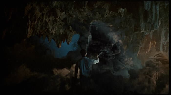 a man standing in front of a cave filled with smoke