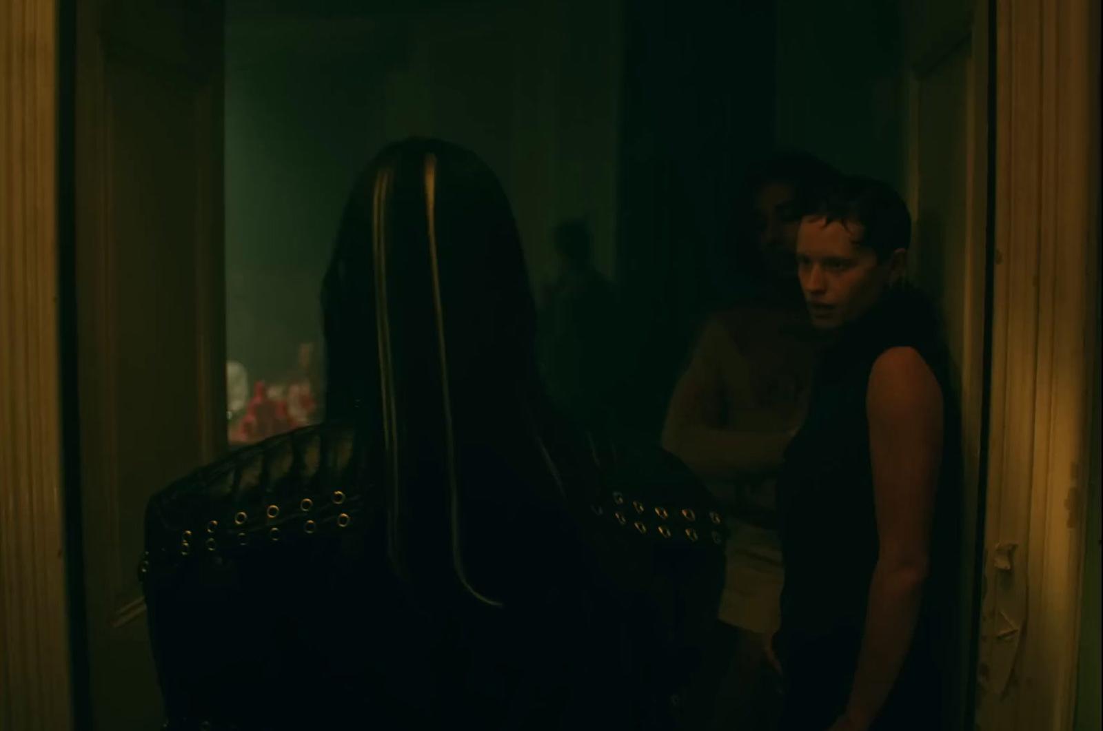 a man standing in a dark room next to a chair