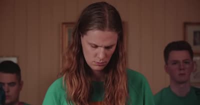 a woman in a green shirt looking at a cell phone