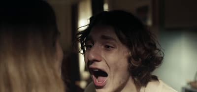 a woman making a face at a man in a kitchen