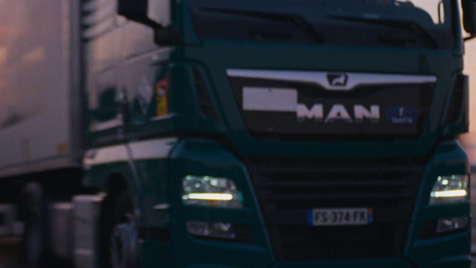 a green semi truck driving down a street