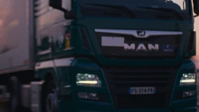 a green semi truck driving down a street