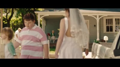 a woman in a wedding dress and a man in a pink and white striped shirt