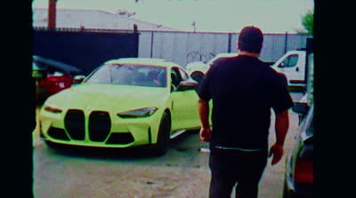 a man standing next to a yellow car in a parking lot