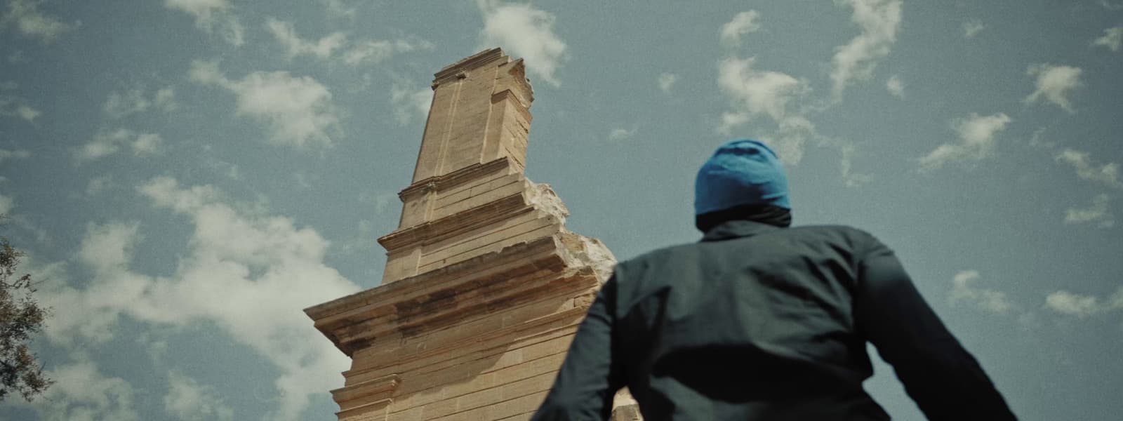 a man in a blue hat is looking up at a tall tower