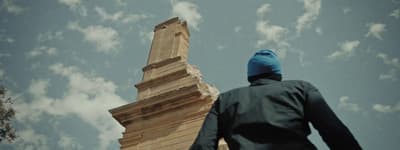 a man in a blue hat is looking up at a tall tower