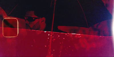 a man with sunglasses and a black umbrella