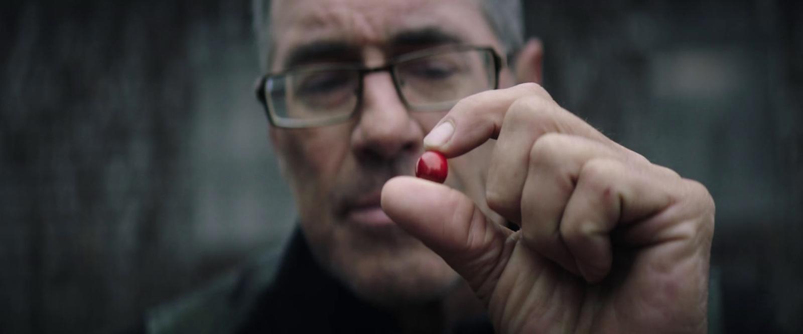a man with glasses holding a cigarette in his hand