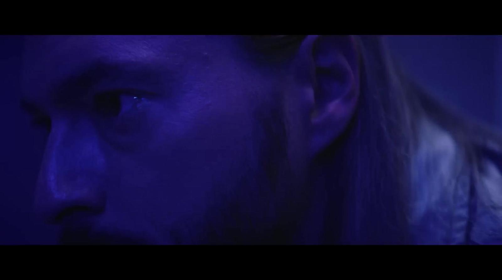 a man with long hair and a beard in a dark room
