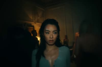 a woman standing in a dark room looking at the camera