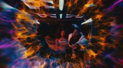 a close up of a person's face with fire and flames in the background