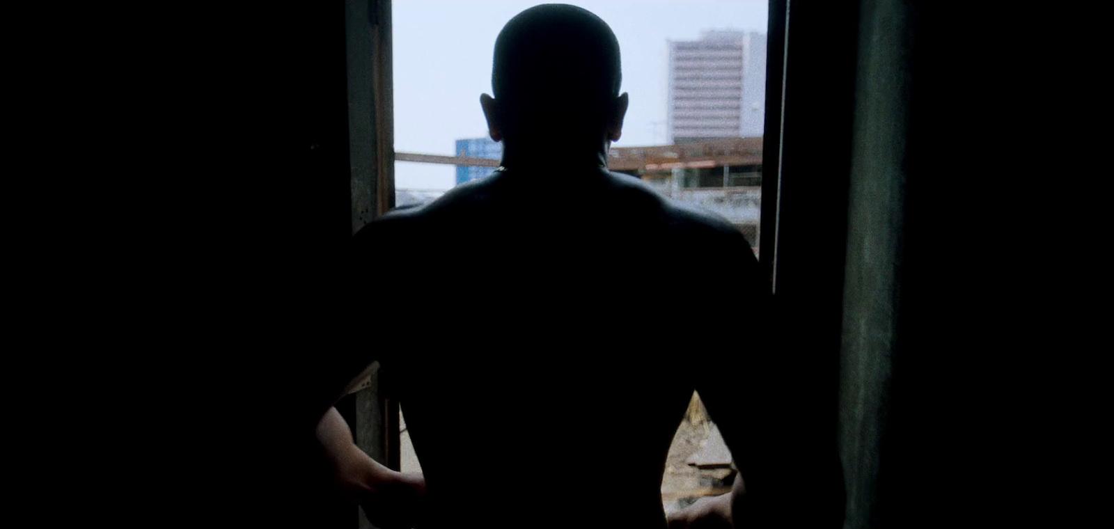 a man standing in front of a window in a dark room