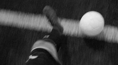 a black and white photo of a person kicking a soccer ball