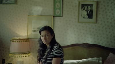 a woman standing in a bedroom next to a bed