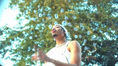 a woman standing in front of a tree blowing bubbles
