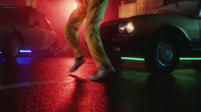 a person in yellow pants and white sneakers walking across a street