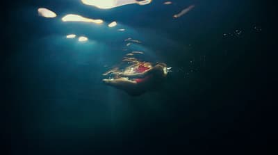a person swimming in the water under a light