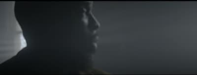 a man standing in a dark room with his head turned to the side