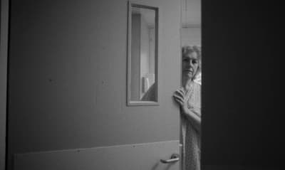 a woman standing in a doorway talking on a cell phone