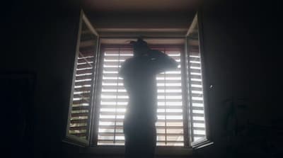 a person standing in front of a window with blinds