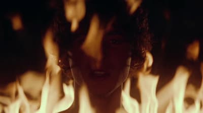 a woman standing in front of a bunch of flames