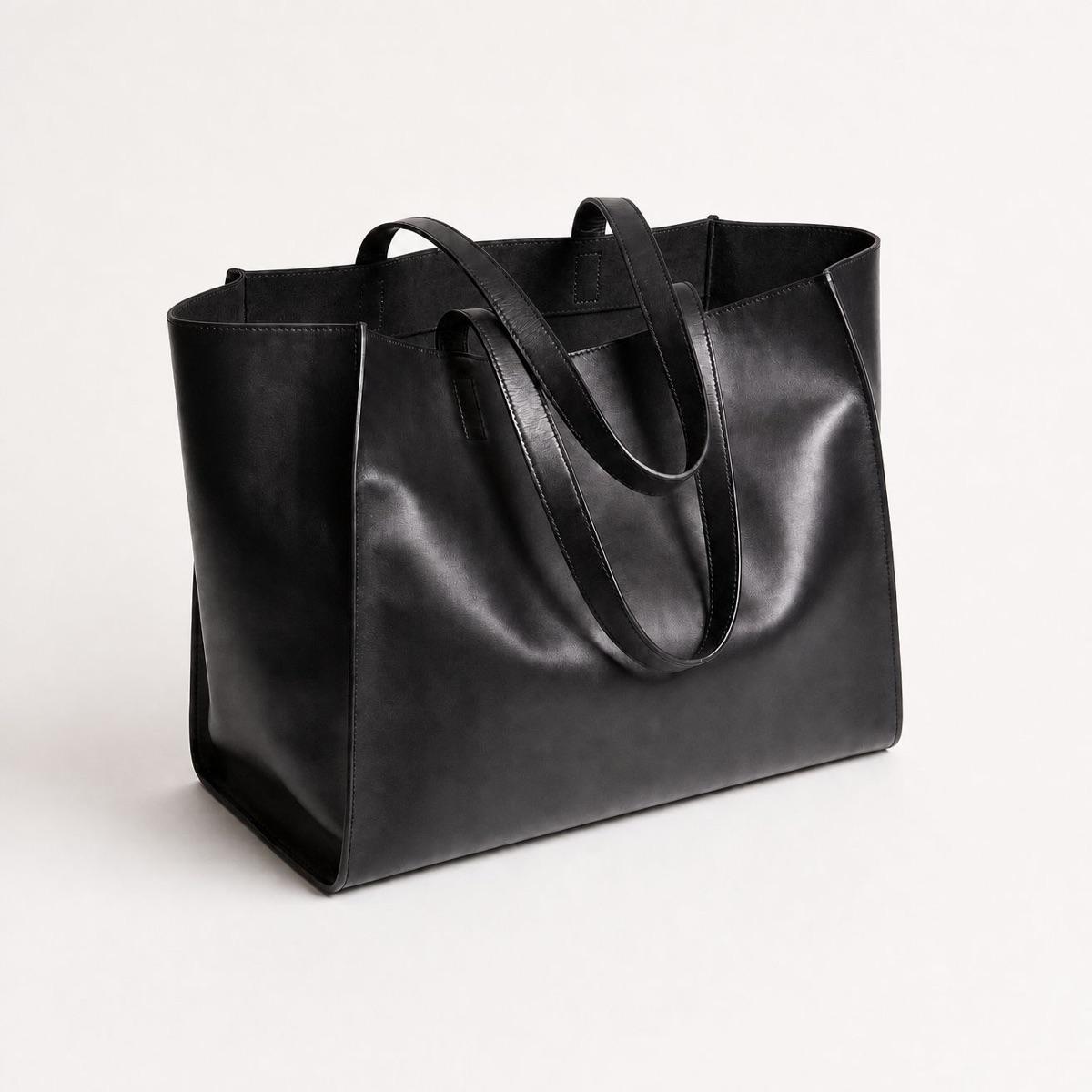Black tote bag staged hanging on a wooden cafe chair in a sunlit interior - After