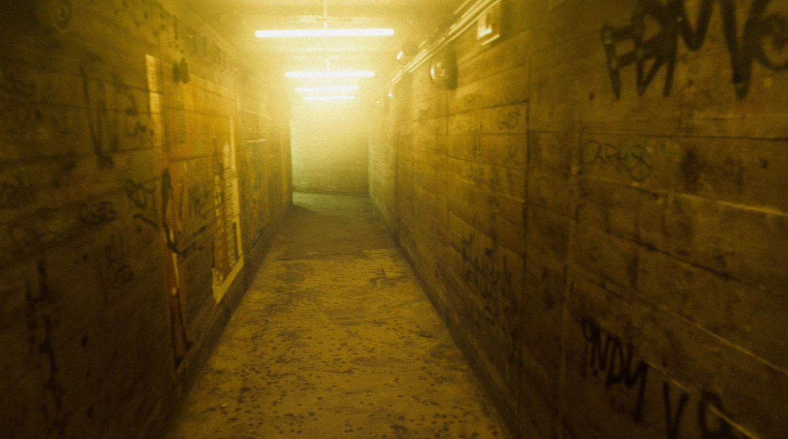 a long narrow hallway with graffiti on the walls